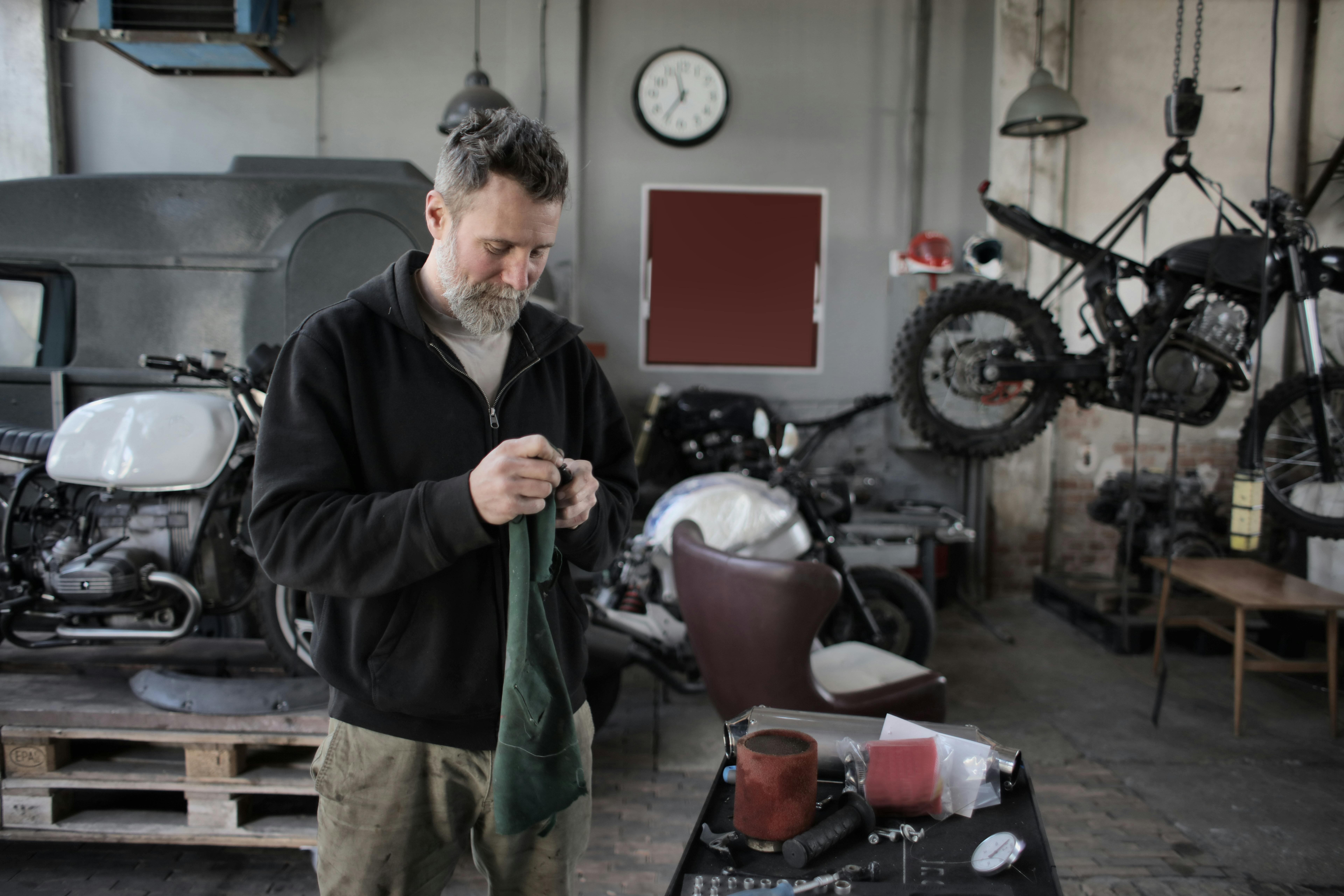 Mechanic focused on repairing motorcycles in an industrial workshop setting.