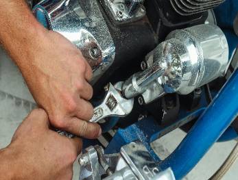 bustling repairs workshop, lively atmosphere, methodically organized, photorealistic, aluminum workbenches and hanging lights, highly detailed, tools scattered amidst gears, vibrant realism, metallic colors, fluorescent lighting, shot with a 35mm lens.