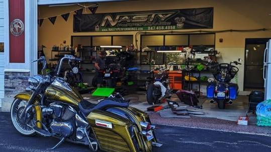 reliable repairs maintenance, thoughtful expression, confidently assessing, photorealistic, well-stocked shelves with neatly arranged tools, highly detailed, dust particles illuminated in the air, functional aesthetic, neutral colors, natural window lighting, shot with a 24mm lens.