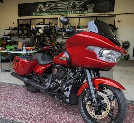 motorcycle repair in progress, frustrated expression, dealing with stubborn bolt, photorealistic, garage with industrial shelving and LED lights under shelves, highly detailed, clatter of tools, telephoto lens, high contrast colors, fluorescent lighting